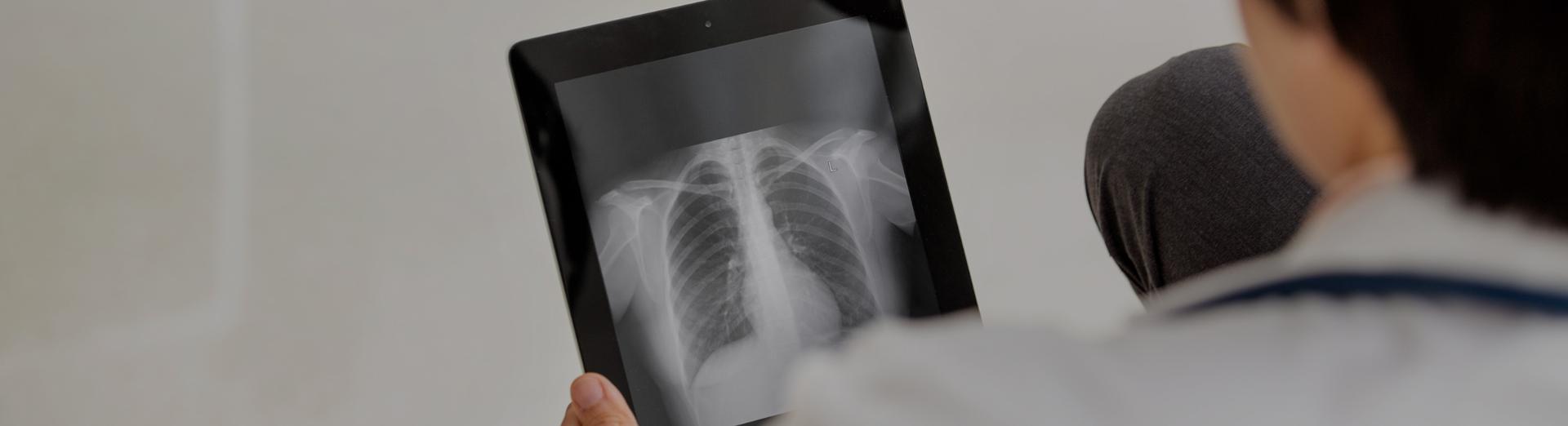 Foto eines Arztes, der ein Röntgenbild auf einem mobilen Gerät begutachtet